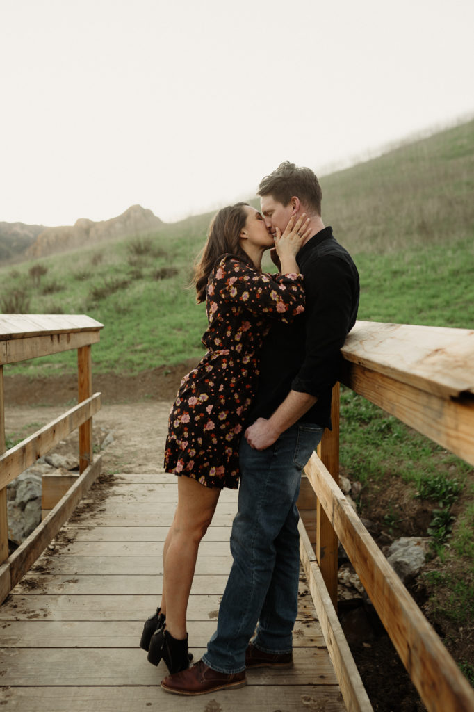 engaged couple romantic kiss on a bridge