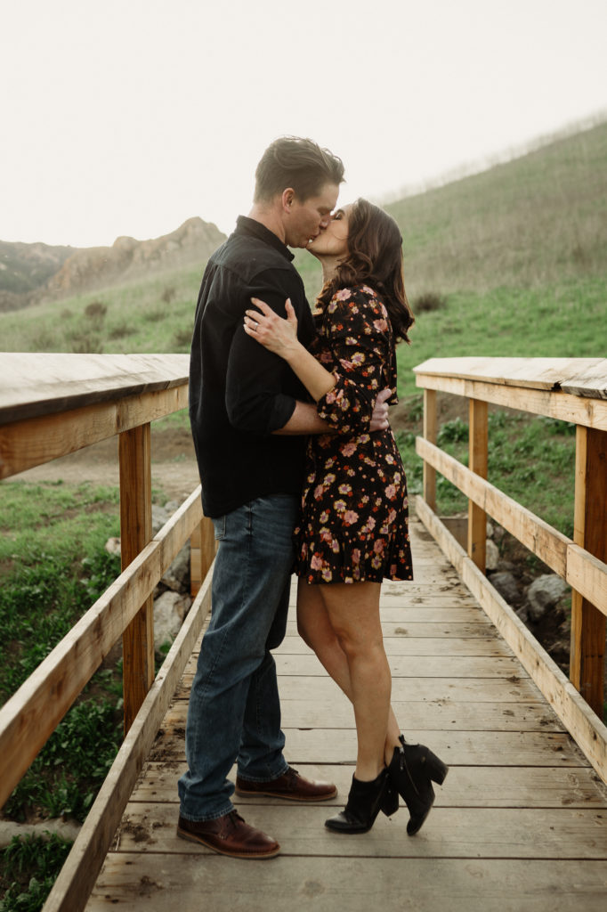 engaged couple romantic kiss on a bridge