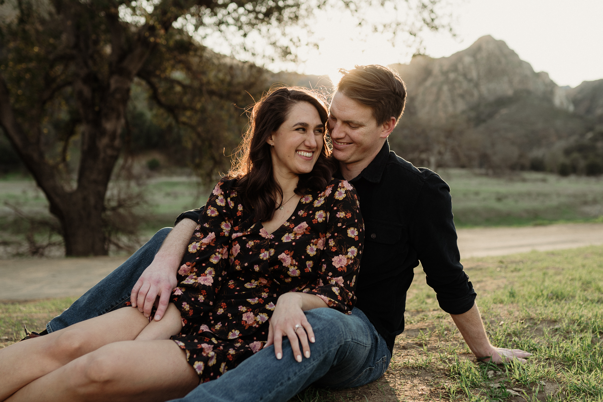 happy couple sitting on the ground at malibu creek state park on a trail