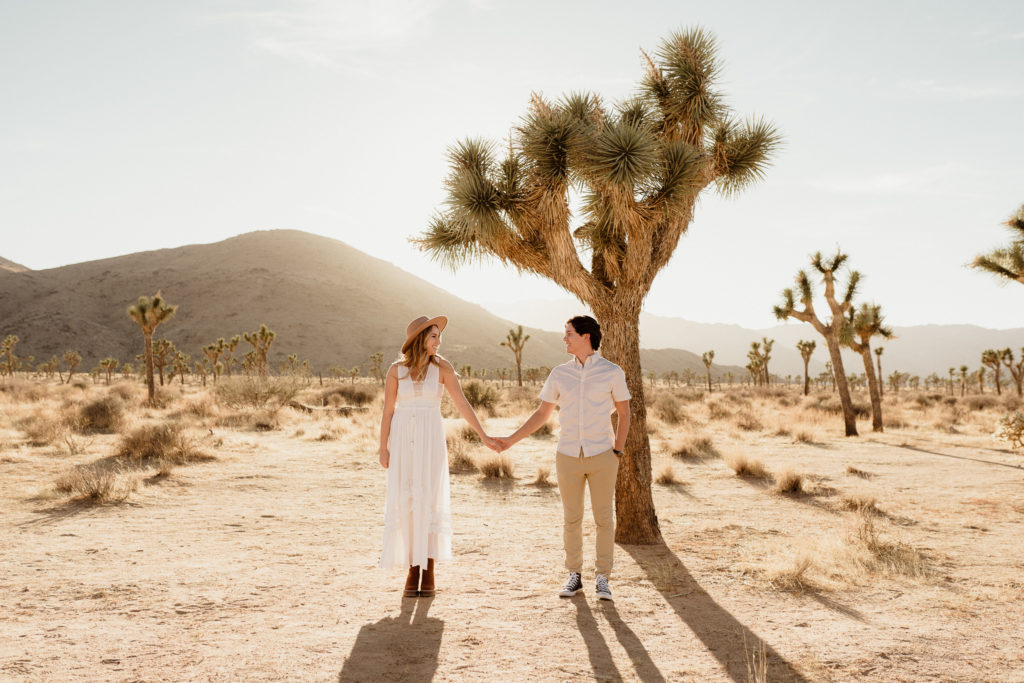 bride and groom couple pose for engagement photos in joshua tree national park in front of an iconia joshua tree