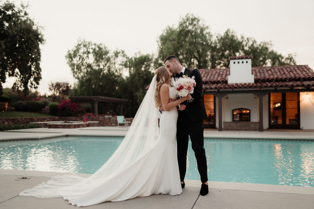 bride and groom kiss in front of pool house at quail ranch wedding venue