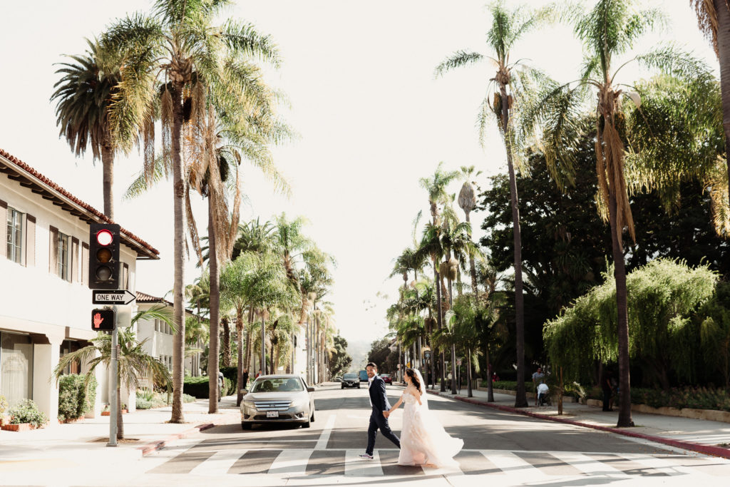 bride and groom who just eloped holding hands running acroos the street in Los Angeles in a crosswalk