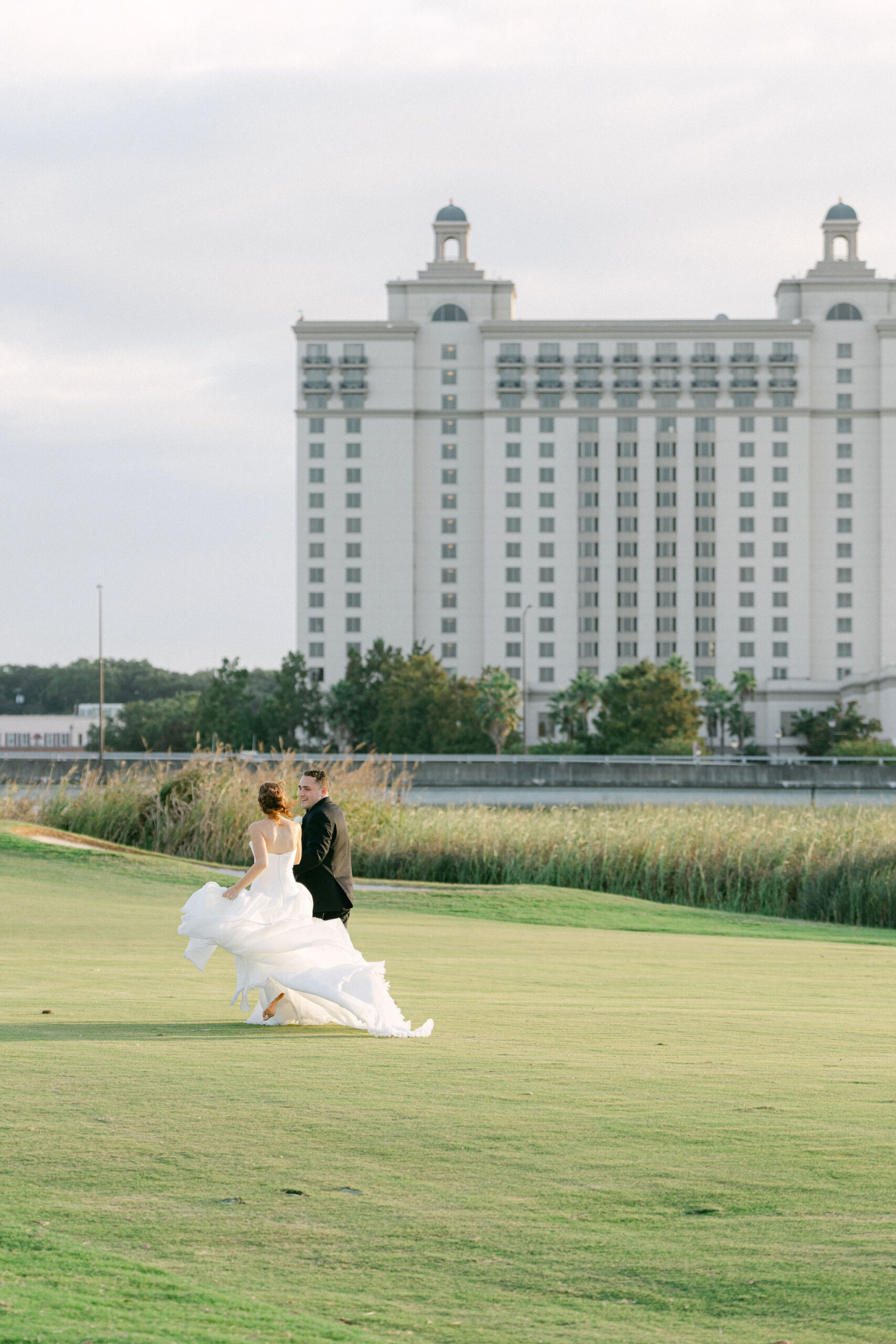 a couple running across the grass at the westin savannah resort during golden hour a their wedding. captured by savannah wedding photographer magnolia west photography